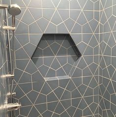 the shower is decorated with white and gray tiles on it's walls, along with a hexagon shaped glass window