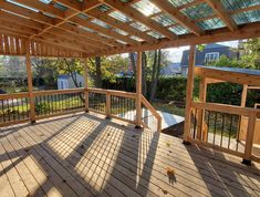 a wooden deck with metal railings under a pergolated roof