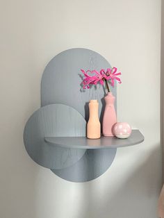 two vases are sitting on a shelf next to a pink flower in a vase