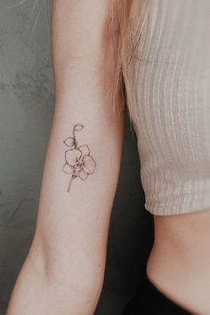 a woman's arm with a small flower tattoo on the left side of her arm