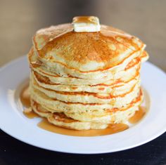 a stack of pancakes covered in syrup on a white plate