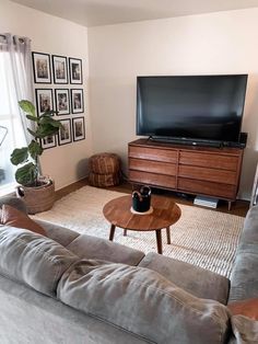 a living room with a couch, coffee table and large television on the far wall