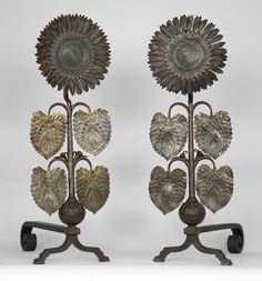 two metal vases with hearts and sunflowers on them, one is standing upright