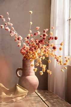 a vase filled with flowers sitting on top of a wooden table next to a window