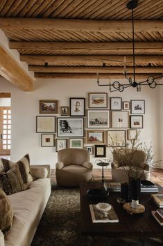 a living room filled with furniture and framed pictures on the wall above it's coffee table