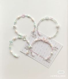 three bracelets with flowers and pearls are on a white surface, one has a card that says happy birthday