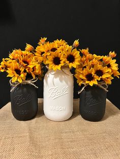 three mason jars with sunflowers in them sitting on a burlap table