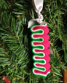 an ornament hanging from a christmas tree decorated with red, green and white yarn