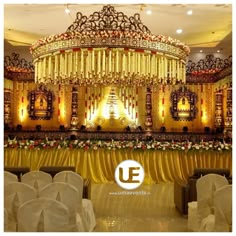 an elaborately decorated stage with white chairs and gold draping on the ceiling