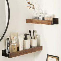 two wooden shelves with soap, toothbrushes and other items on them in front of a mirror