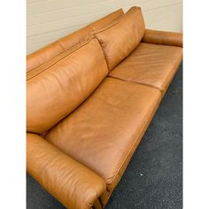 a brown leather couch sitting on top of a black floor next to a white wall