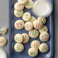 cookies with sprinkles on a blue plate next to a glass of milk