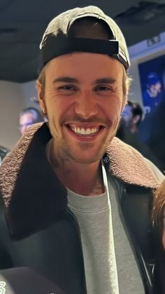 a man with a hat and jacket smiling at the camera