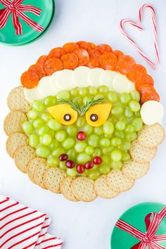 a platter with grapes, carrots and crackers in the shape of a face