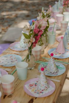 a wooden table topped with plates and cups