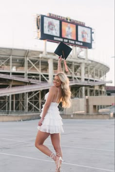 a woman in a white dress is holding up a black book and posing for the camera