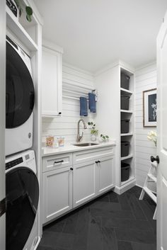 a washer and dryer in a white laundry room with black tile flooring