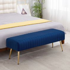 a blue bench sitting on top of a bed next to a white headboard and foot board