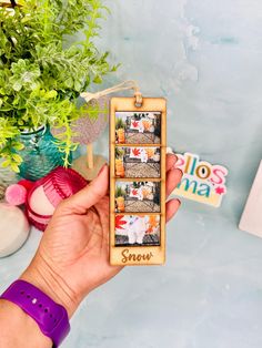 a hand holding up a wooden photo frame with photos on it and the words snow