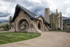 a large stone building with arched windows on the front and side, surrounded by lush green grass