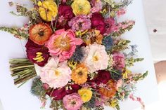 a bouquet of flowers sitting on top of a white table next to a person's hand