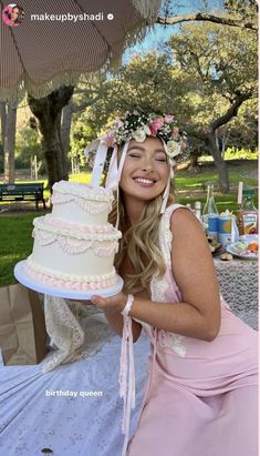 a woman in a pink dress is holding a cake