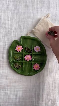 a green tray with pink flowers on it and a person's hand next to it