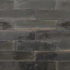 a black brick wall that has been cleaned and sealed with some water on the floor