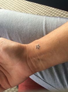 a person with a small star tattoo on their left wrist, sitting down and looking at the camera