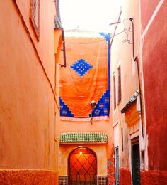 a narrow alleyway with an orange and blue banner hanging from the ceiling above it