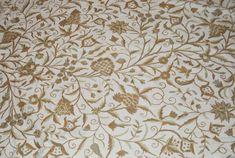 an intricately designed wallpaper with gold and white flowers on it's side