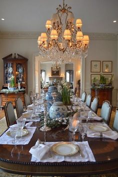 the dining room table is set with place settings for six people and there are chandeliers hanging from the ceiling