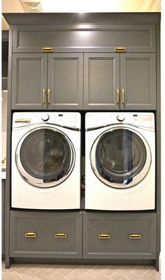 a washer and dryer sitting in front of gray cabinets