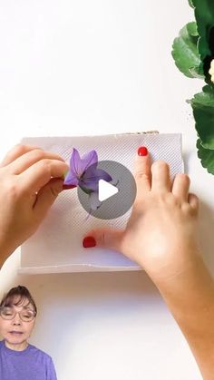 a woman is making a paper flower decoration