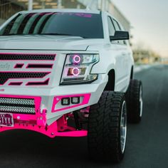 the front end of a white truck with pink lights on it's bumpers