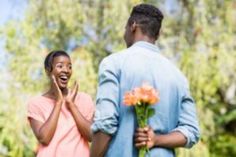 a man and woman standing next to each other with flowers in front of their faces