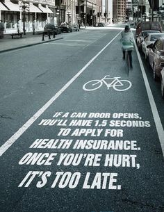 a person riding a bike down a street next to parked cars and bicycles on the road