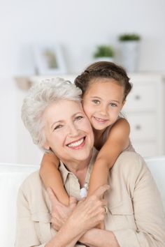 an older woman hugging her granddaughter on the couch