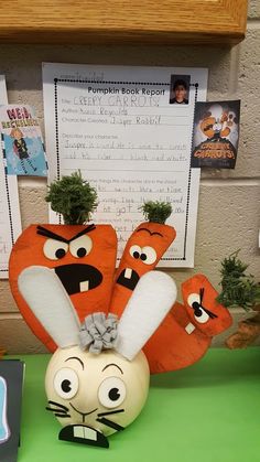 an orange and white stuffed animal sitting on top of a green table next to a planter