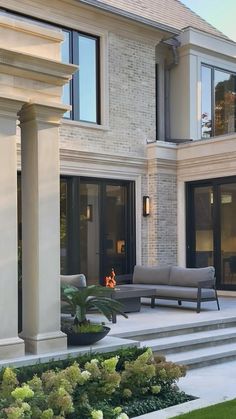 an outdoor living area with couches, chairs and plants in front of the house