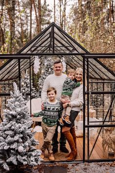 a man, woman and child standing in front of a christmas tree with snow on the ground