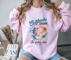 Show your love California with this graphic sweatshirt. Wear out with friends and family, while running errands, during your travels, or just on days when you want to lounge around at home. Also, a great gift idea for anyone special in your life. - Recommended that you size UP for a looser fit. - Made from 60% polyester, 40% cotton. - Collar is ribbed knit, so it retains its shape even after washing.  - Made with a medium-heavy fabric blend of 50% cotton and 50% polyester (8.0 oz/yd² (271.25 g/m²). - Classic fit along with a crew neckline.  - Needle stitching at the shoulder, armhole, neck, waistband, and cuff seams. - Made using 100% ethically grown US cotton.  - Gildan is also a proud member of the US Cotton Trust Protocol ensuring ethical and sustainable means of production. - OEKO-TEX- Beach Palm Trees, Golden State, Heavy Fabric, The Golden, Running Errands, Palm Trees, San Jose, Crewneck Sweatshirt, Sweat Shirt