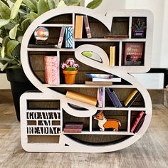 the letter s is made out of bookshelves and has various items on it