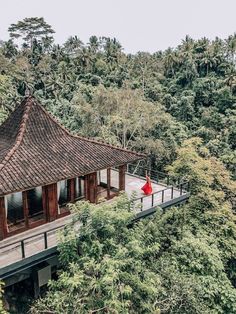 a red umbrella sitting on top of a wooden building in the middle of some trees