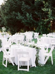 the tables are set with white linens and greenery for an outdoor wedding reception