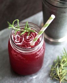 a glass filled with red liquid and garnish