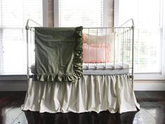 a crib with a blanket and pillows on top of it in front of two windows