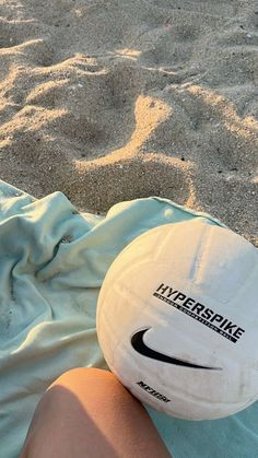 a white frisbee sitting on top of a sandy beach next to a person