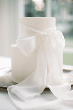 a close up of a white cake on a plate with a ribbon around the top