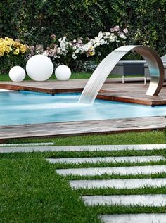 a water fountain in the middle of a pool with steps leading up to it and flowers on either side